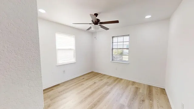 an empty room with windows and fan