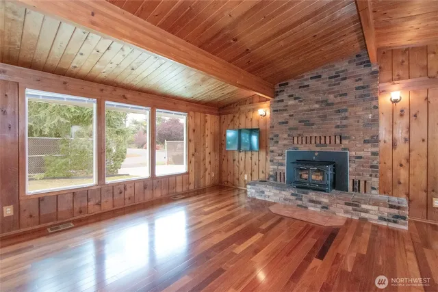 a view of an empty room with wooden floor fireplace and a window