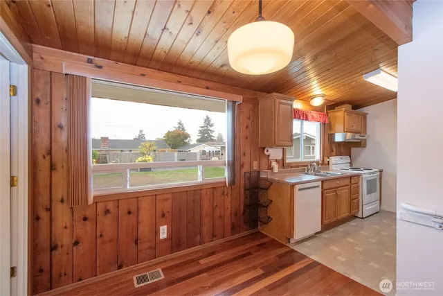 a view of a kitchen with a sink and dishwasher a refrigerator with wooden floor