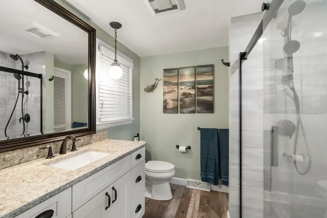 a bathroom with a granite countertop sink toilet and shower