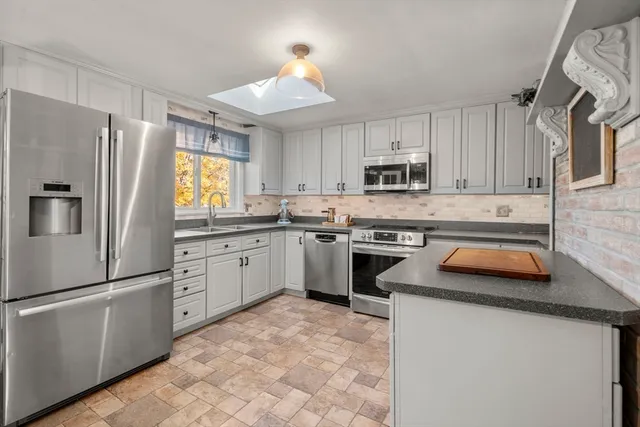 a kitchen with granite countertop a stove sink and refrigerator