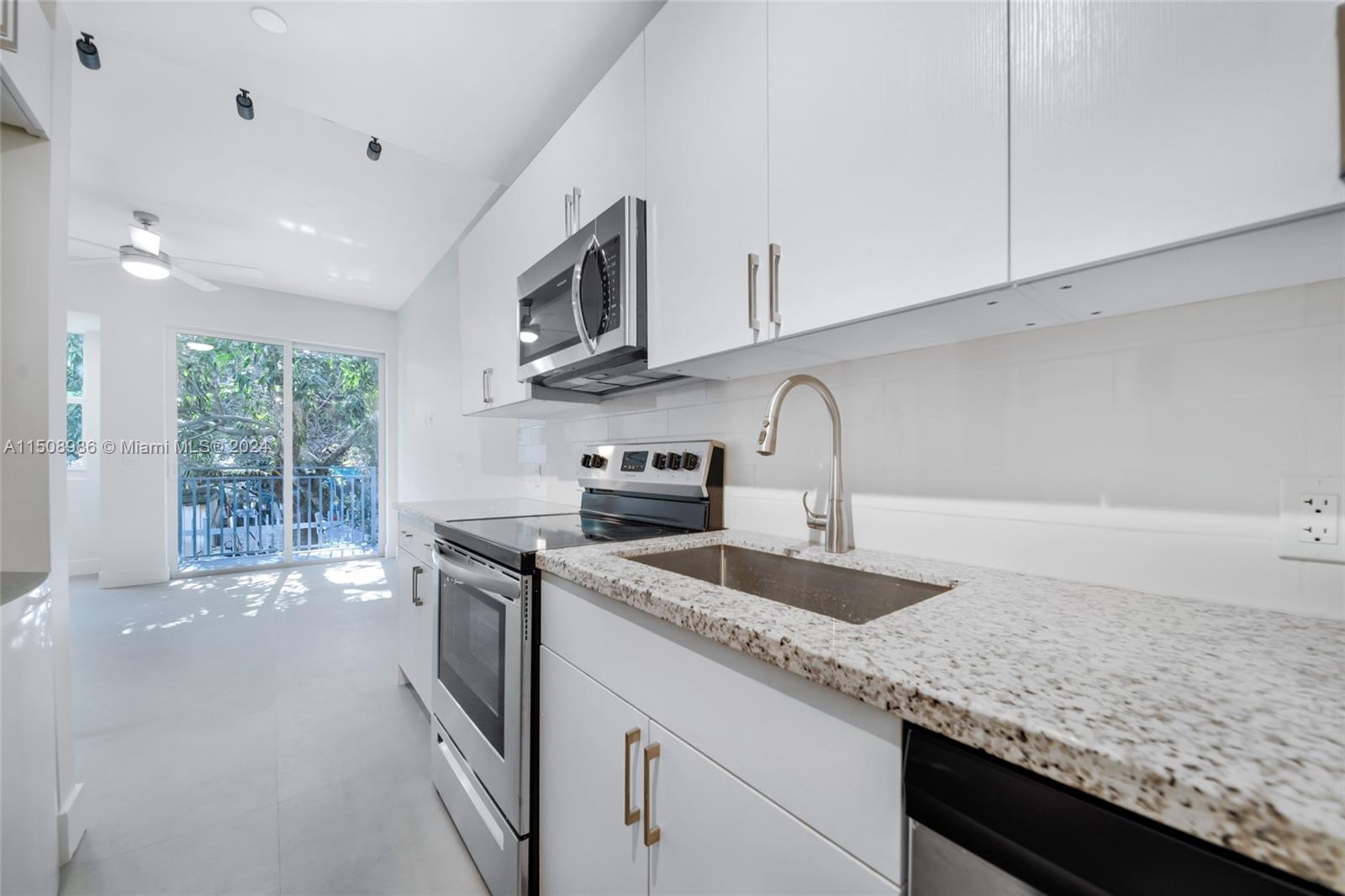 a kitchen with granite countertop a sink stainless steel appliances white cabinets and a granite counter tops
