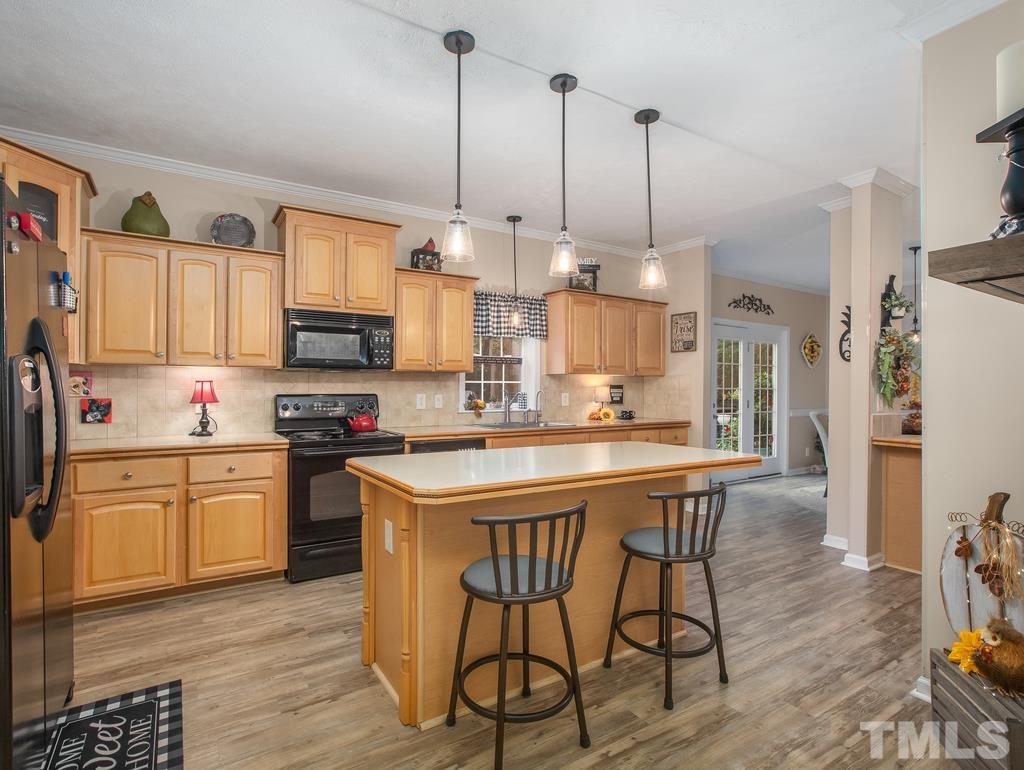 2525 Baptist Road Durham, NC 27703 - Photo 10 of 23 a kitchen with stainless steel appliances kitchen island granite countertop a sink a stove a dining table and chairs with wooden floor