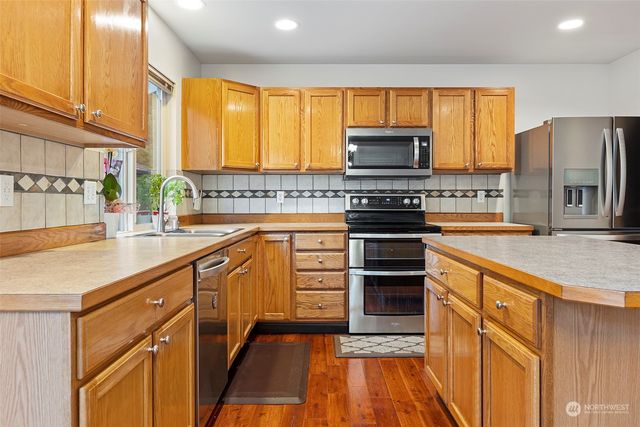 a kitchen with stainless steel appliances granite countertop a stove a sink a refrigerator and island