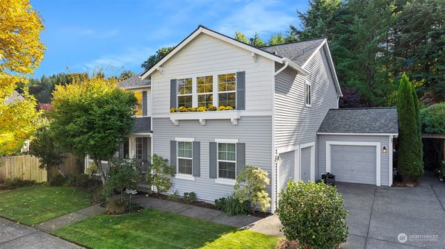 a view of a house with a small yard and large tree