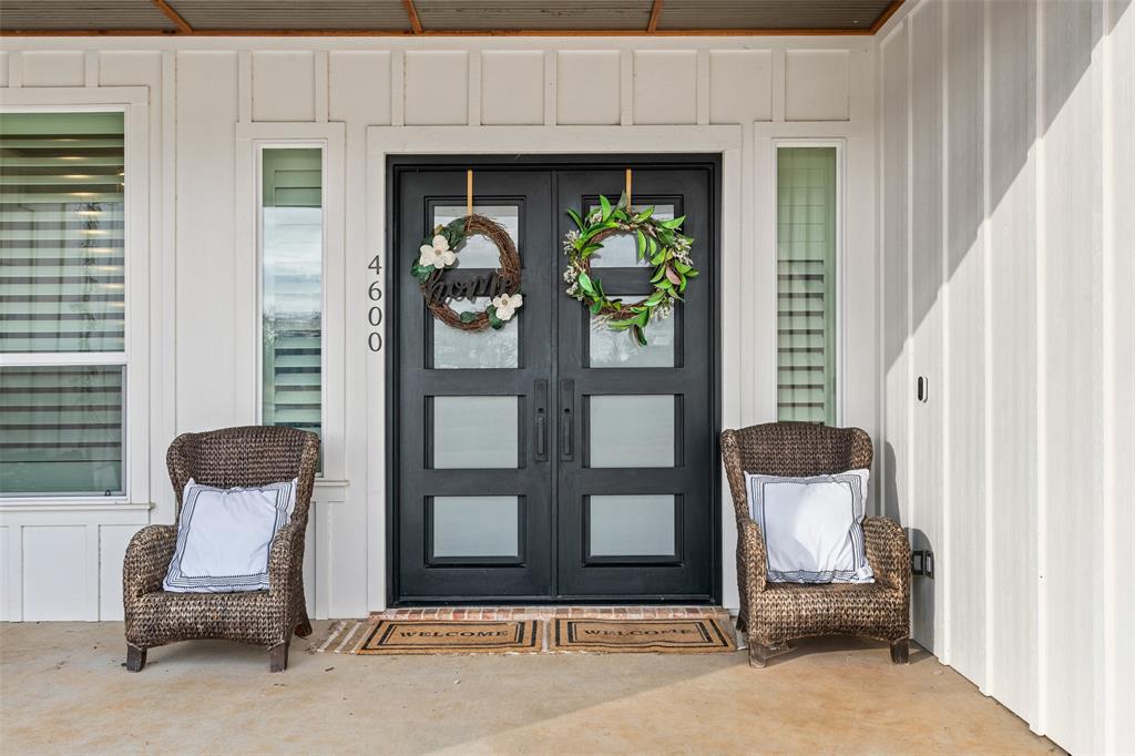 4600 Old Brock Road Weatherford, TX 76087 - Photo 5 of 37 Double entry doors with frosted glass panels, board and batten siding, vertical side lights, large windows with horizontal blinds, and a concrete porch