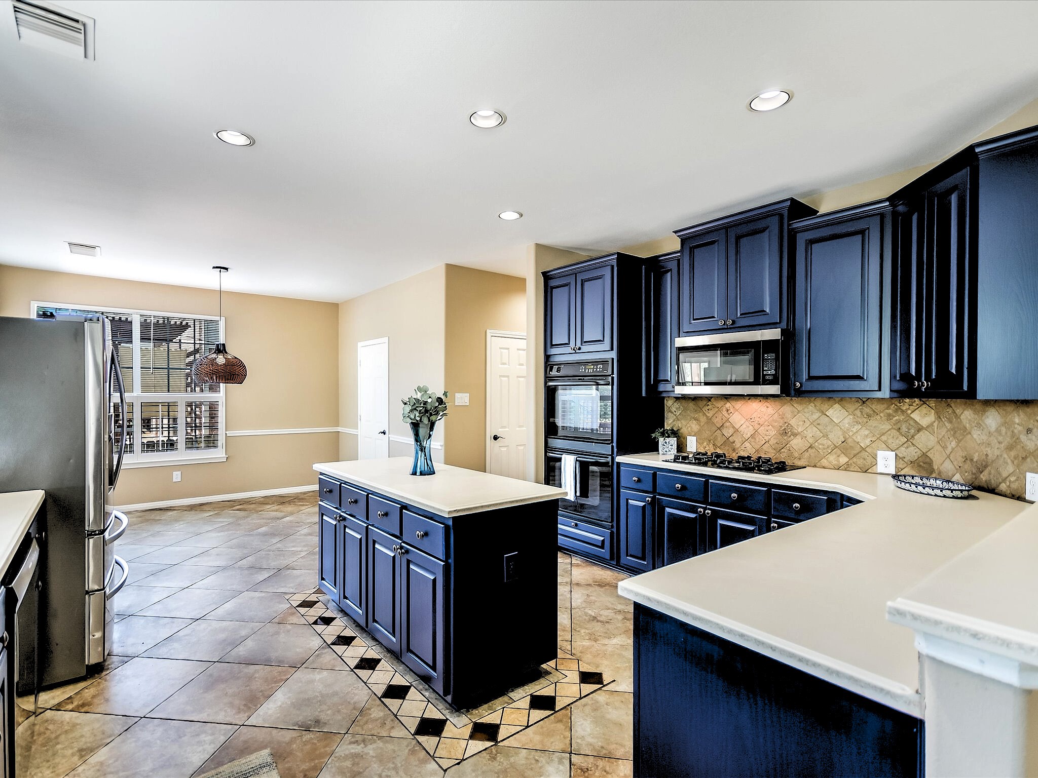 12935 Brigham Drive Austin, TX 78732 - Photo 3 of 35 Kitchen - features sophisticated navy blue cabinetry (darker blue in person than in photo), white Corian countertops, gas cooktop, double oven, microwave, stainless steel refrigerator, breakfast bar, and a walk-in pantry