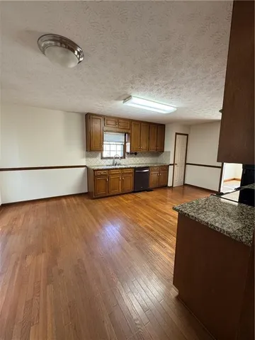 a large kitchen with kitchen island a sink dishwasher a stove and a wooden floor