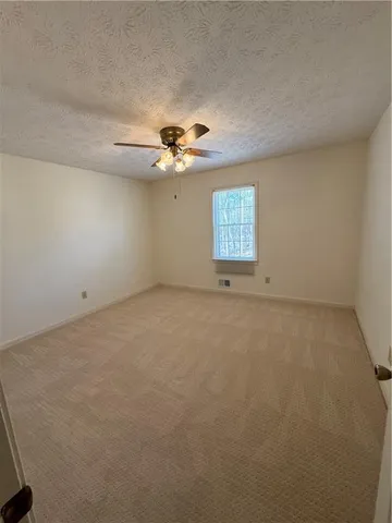 an empty room with windows and ceiling fan