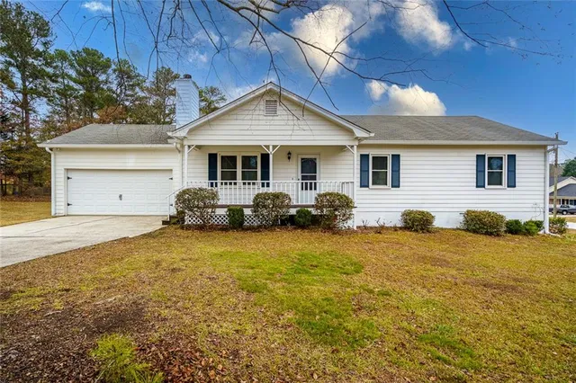 a front view of house with yard and trees in the background