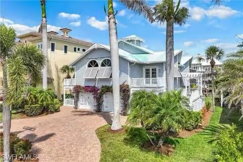 437 Trade Winds Avenue Naples, FL 34108 - Photo 1 of 33 a front view of a house with a garden and trees