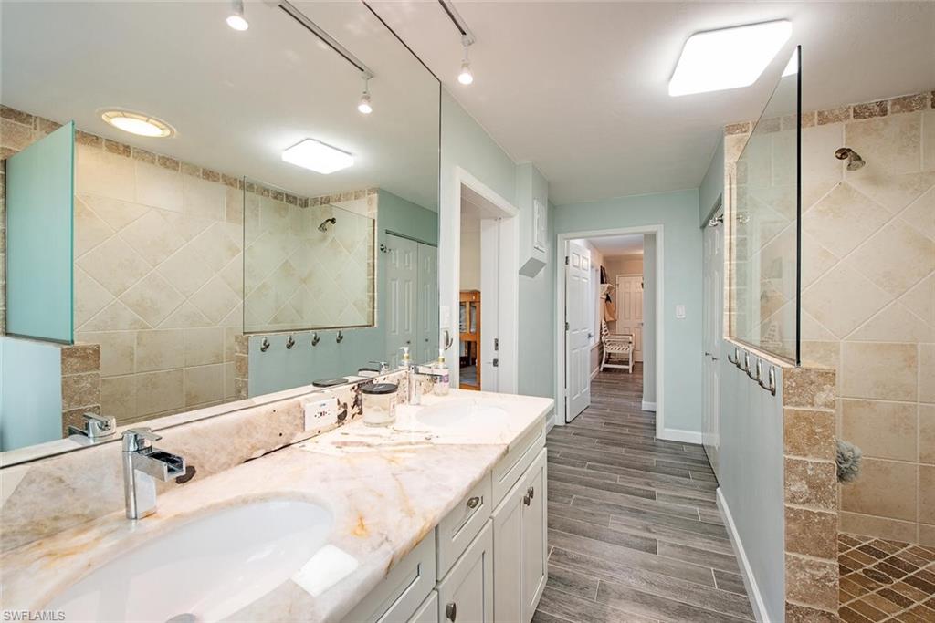 437 Trade Winds Avenue Naples, FL 34108 - Photo 22 of 33 a bathroom with a double vanity sink a mirror and shower
