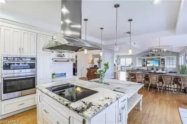 a kitchen with stainless steel appliances granite countertop a sink a stove and a wooden floors