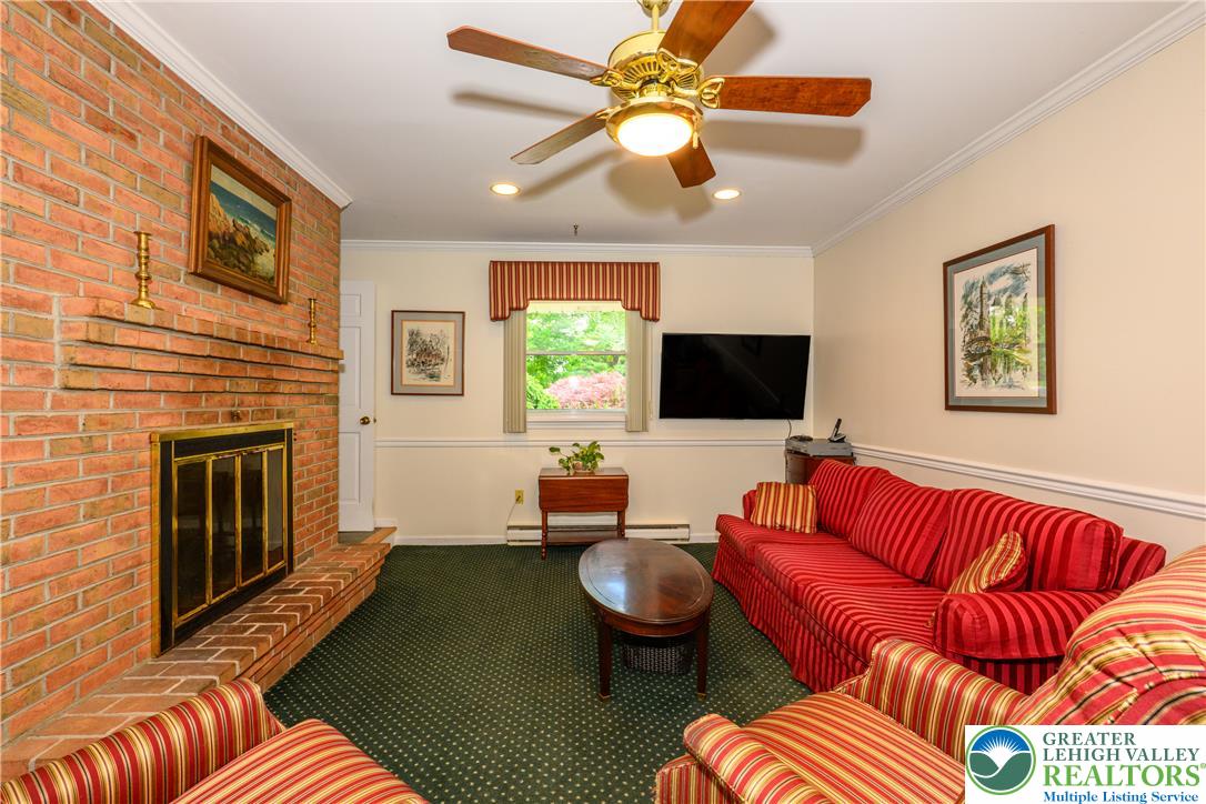 2516 Rachael Lane Orefield, PA 18069 - Photo 17 of 45 A comforting living room features a brick fireplace, a window overlooking greenery, and a cozy ceiling fan.