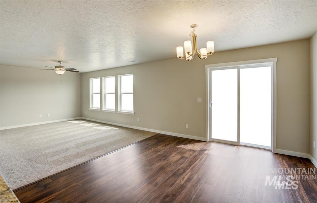 1589 Witt Mountain Mountain Home, ID 83647 - Photo 5 of 7 Unfurnished room featuring a chandelier, a textured ceiling, dark wood finished floors, and ceiling fan