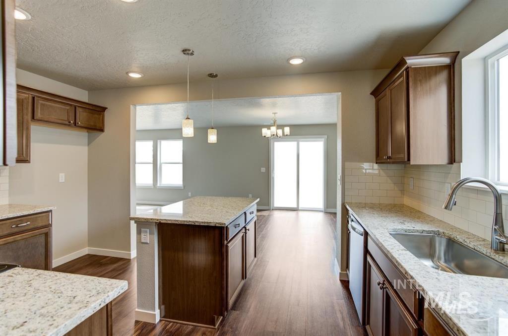 1589 Witt Mountain Mountain Home, ID 83647 - Photo 6 of 7 Kitchen featuring dishwasher, backsplash, a textured ceiling, dark wood-style floors, and decorative light fixtures