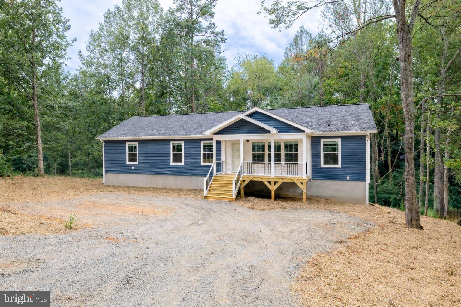 a front view of a house with yard and trees in the background