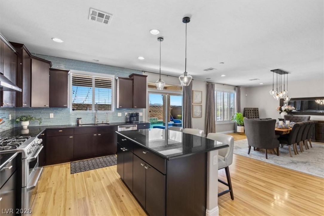10334 Mopan Road Las Vegas, NV 89178 - Photo 11 of 28 The kitchen offers a granite island, glass tile backsplash, and stainless appliances, open to the dining and living areas.