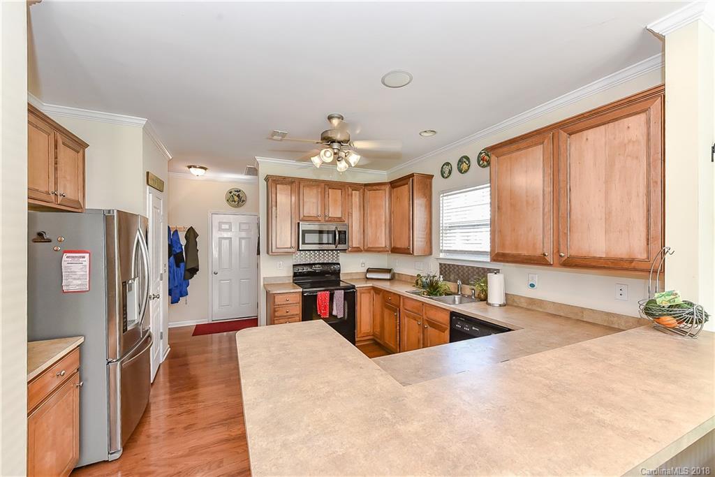 325 Sand Paver Way, Unit 99 Fort Mill, SC 29708 - Photo 11 of 25 a large kitchen with stainless steel appliances kitchen island granite countertop a refrigerator a sink dishwasher a stove and a dining table with wooden floor
