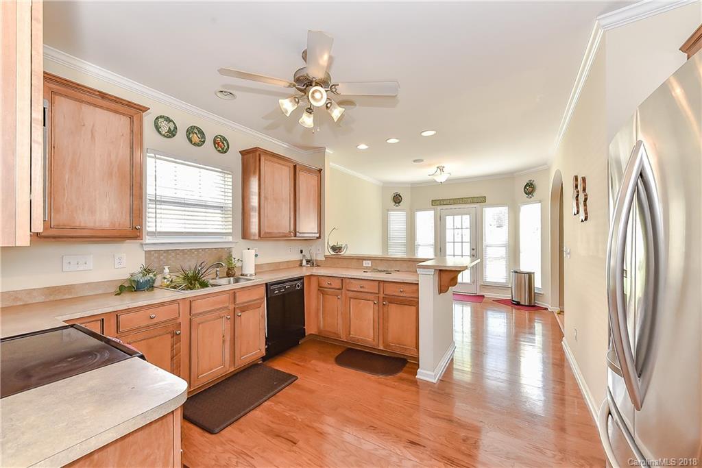 325 Sand Paver Way, Unit 99 Fort Mill, SC 29708 - Photo 15 of 25 a large kitchen with stainless steel appliances granite countertop a refrigerator a sink dishwasher a dining table and chairs with wooden floor