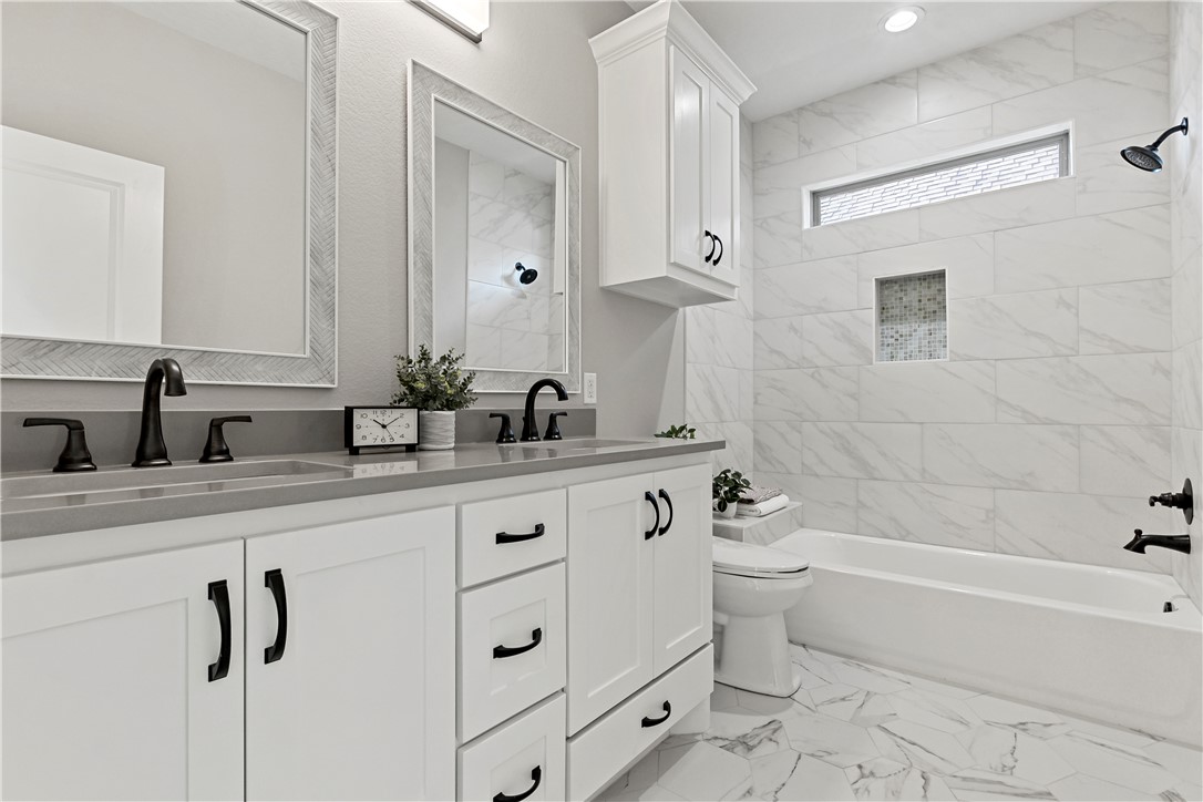 2912 GOLDBERG Drive Bryan, TX 77808 - Photo 20 of 35 a bathroom with a double vanity sink a toilet a mirror and shower