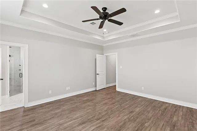 an empty room with wooden floor ceiling fan and windows