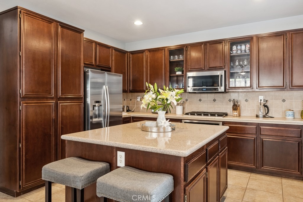 38790 Cobblestone Circle Murrieta, CA 92563 - Photo 14 of 43 a kitchen with stainless steel appliances a sink stove refrigerator dining table and chairs