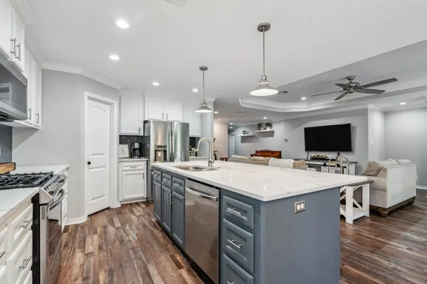 a kitchen with a stove a refrigerator and a flat screen tv