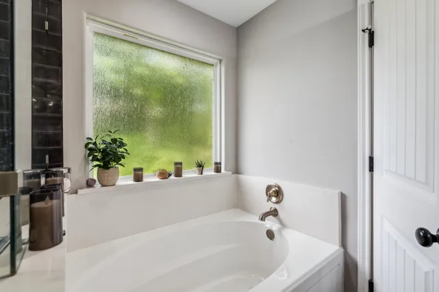 a white bath tub sitting in a bathroom next to a window