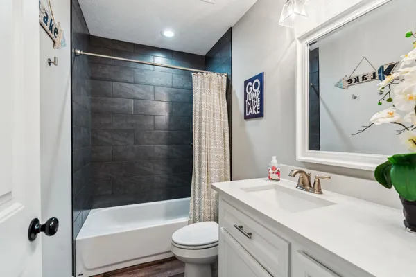 a bathroom with a bathtub shower sink vanity mirror and toilet