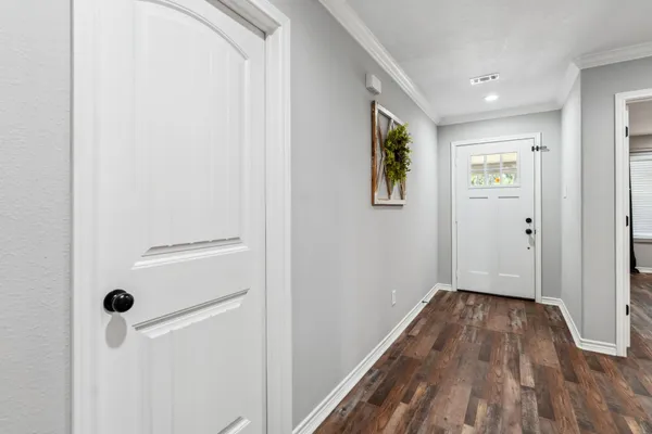a view of a hallway with wooden floor and a bathroom