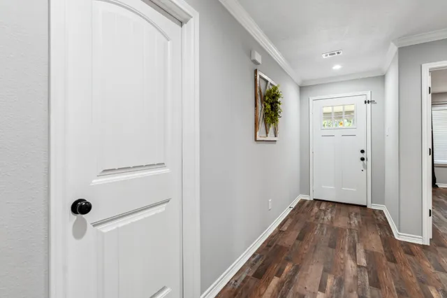 a view of a hallway with wooden floor and a bathroom