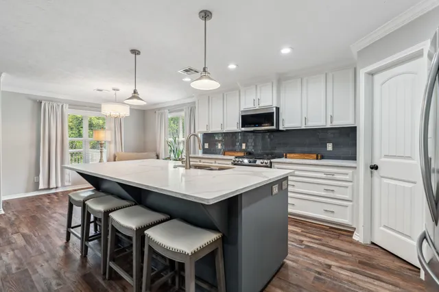 a kitchen with kitchen island granite countertop a sink a center island and appliances