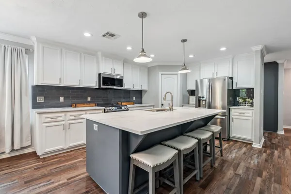 a kitchen with kitchen island granite countertop a sink a center island and stainless steel appliances