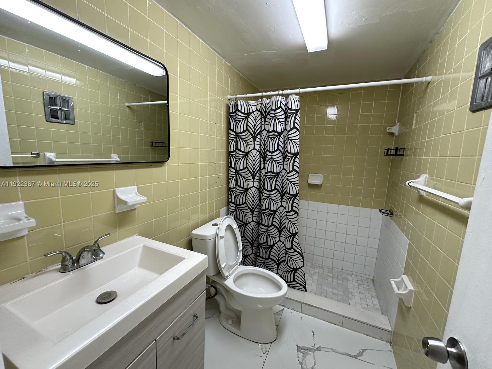 4655 Palm Avenue, Unit 203 Hialeah, FL 33012 - Photo 9 of 16 a bathroom with a sink mirror toilet and shower