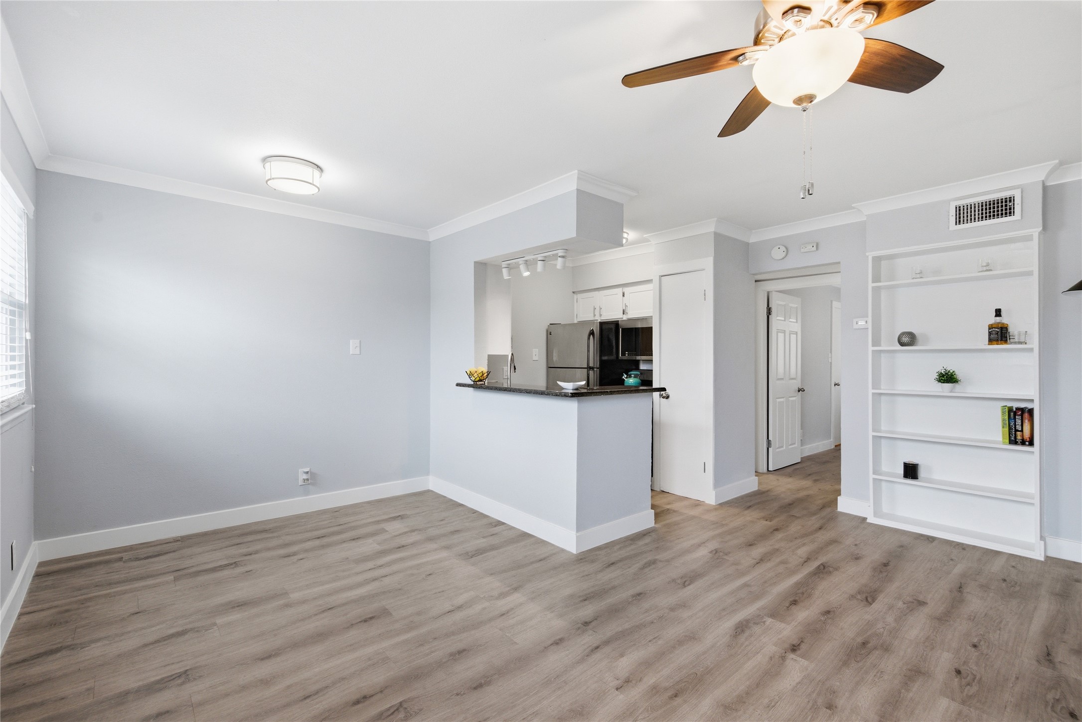 2401 Manor Road, Unit 232 Austin, TX 78722 - Photo 2 of 32 View of dining, kitchen. and living room featuring crown molding, a ceiling fan, built in features, and laminate flooring