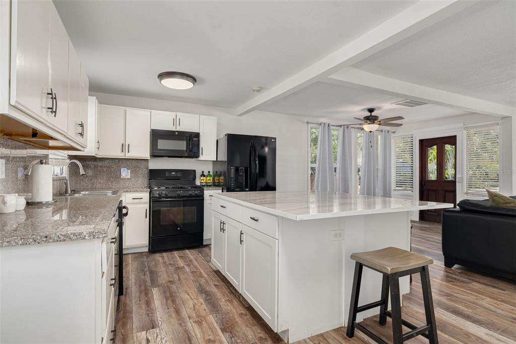 200 Broadway Dunedin, FL 34698 - Photo 14 of 59 a kitchen with stainless steel appliances granite countertop a refrigerator a stove top oven a sink dishwasher and white cabinets with wooden floor
