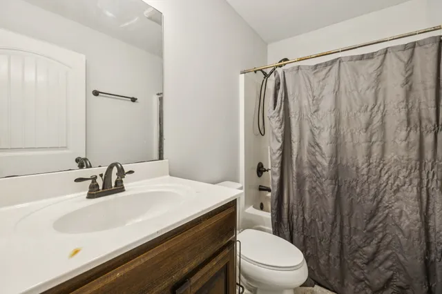 a bathroom with a sink a toilet a mirror and shower curtain