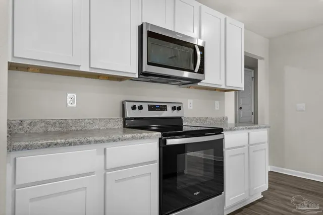a kitchen with stainless steel appliances granite countertop white cabinets granite counter tops and a wooden floors