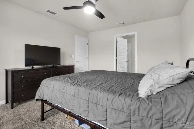 a bedroom with a large bed and a flat tv screen on dresser