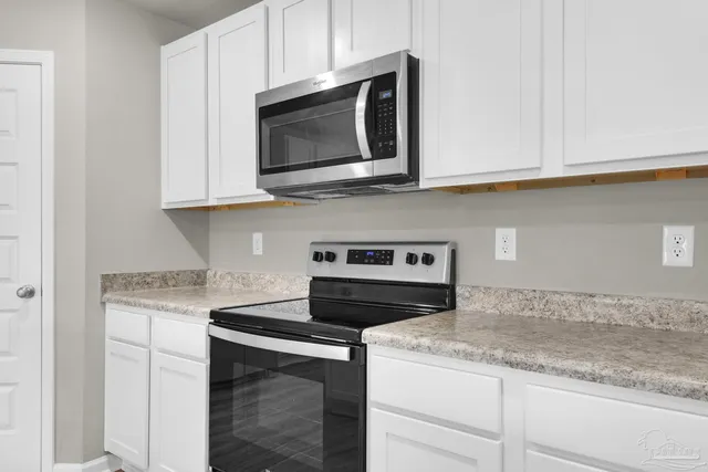 a kitchen with granite countertop white cabinets and a stove top oven