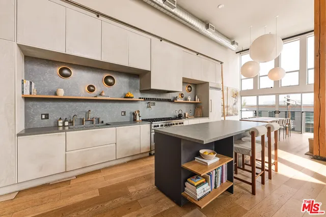 a kitchen with stainless steel appliances granite countertop a stove a sink and a refrigerator with wooden floors