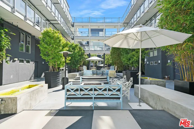 a view of a patio with couches table and chairs under an umbrella