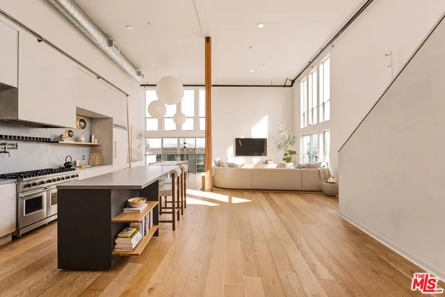 a living room with stainless steel appliances kitchen island granite countertop a sink a kitchen island a stove and a wooden floors