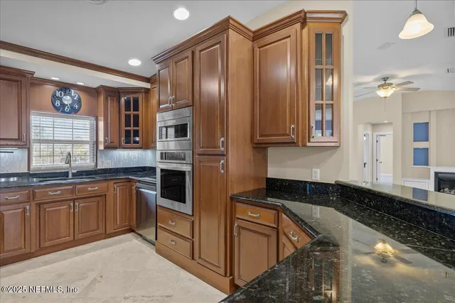 a kitchen with stainless steel appliances granite countertop a refrigerator a stove and a sink with wooden cabinets