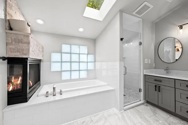 a bathroom with a tub a sink and a large mirror