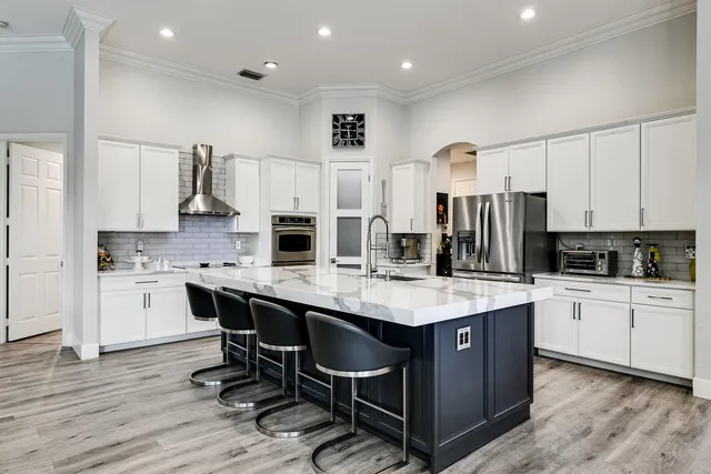 a kitchen with stainless steel appliances kitchen island granite countertop a table chairs sink and cabinets