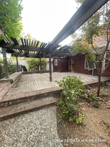 a view of a backyard with table and chairs under an umbrella with large trees