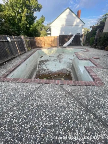 a view of a dry yard with a wooden fence