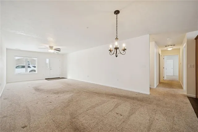 a view of a room with a chandelier fan and windows